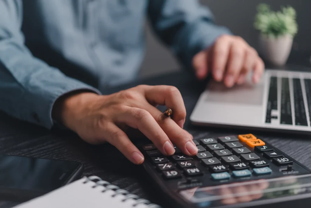 Un homme qui fait des calculs sur une machine avec son ordinateur à côté