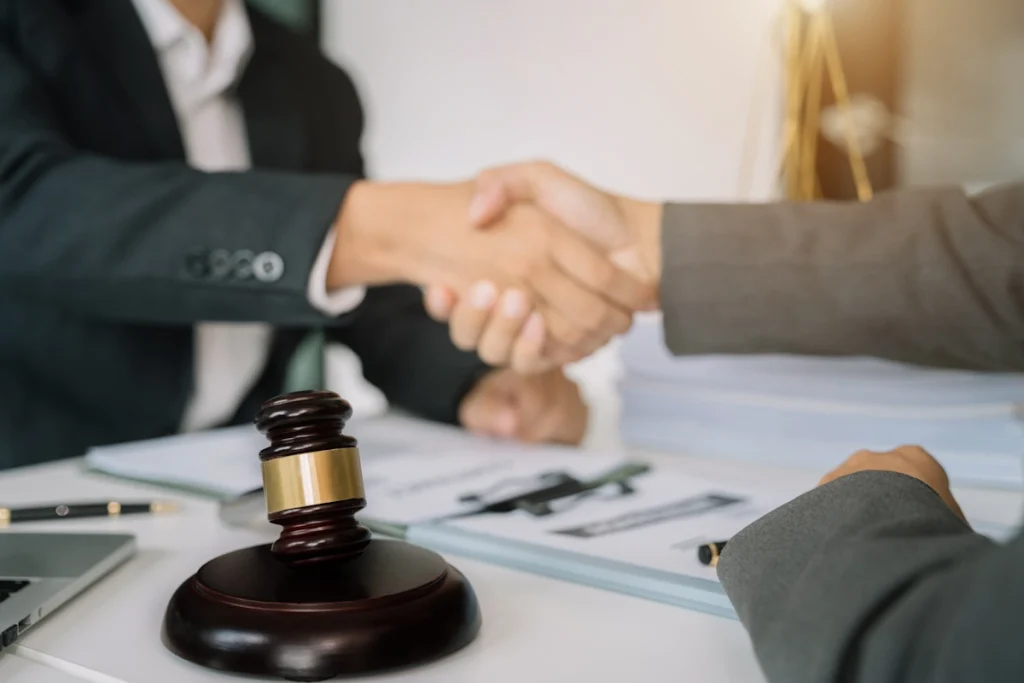 Deux hommes qui se serrent la main à côté d'un marteau de la justice