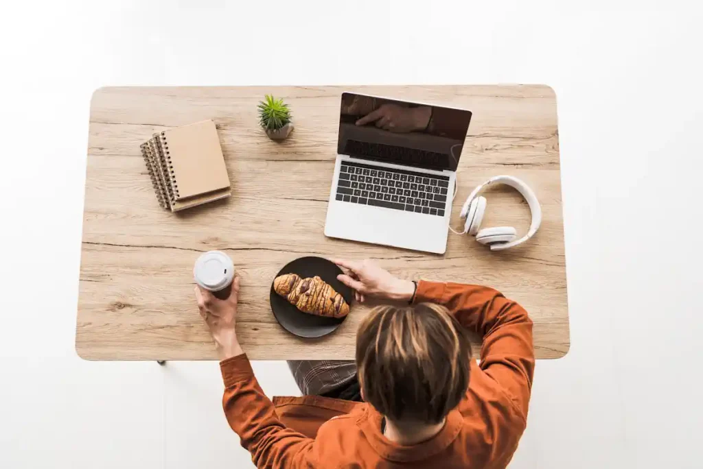Une femme devant son ordinateur avec un croissant et un café