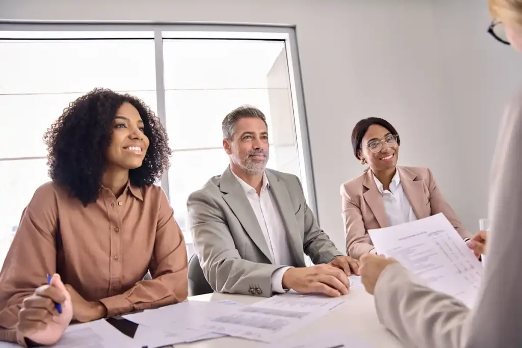 un homme qui regarde un document devant 3 personnes