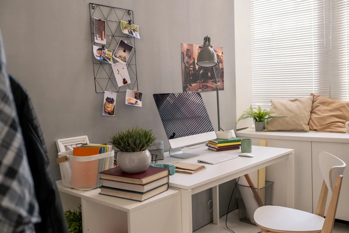 Un bureau avec un ordinateur, des livres, une plante et une lampe
