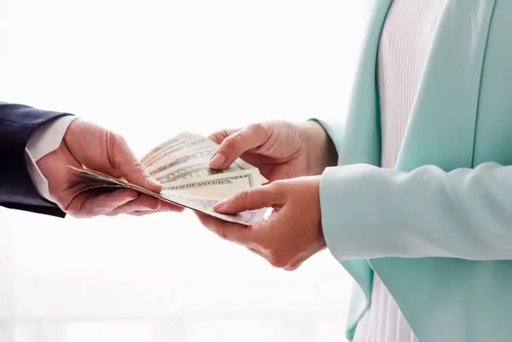 Une personne qui tend des billets d'argent à une aitre qui les prend