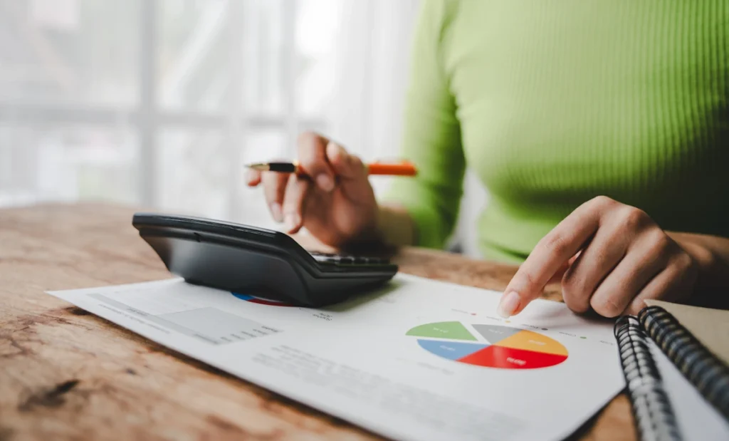 Une femme qui utilise une calculatrice et un graphique sur un papier