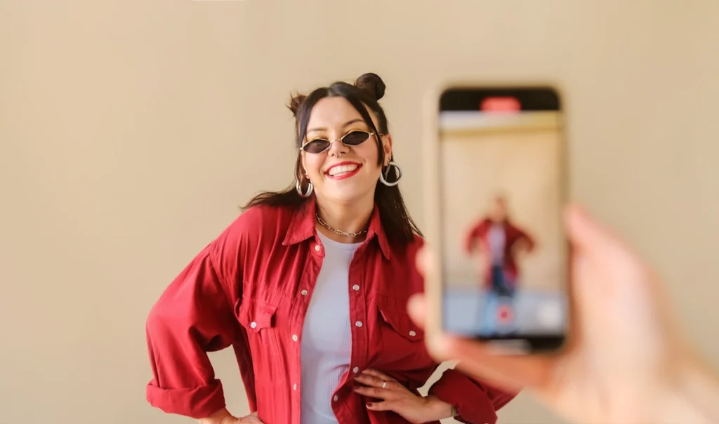Une jeune femme qui se fait filmer avec un téléphone