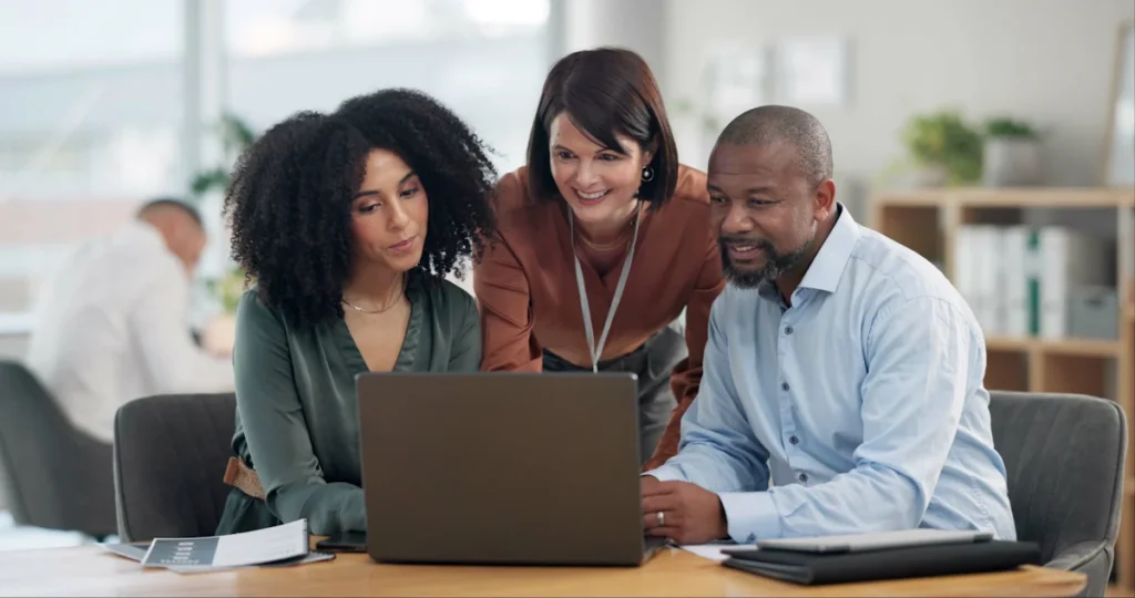 Deux femmes et un homme qui travaillent sur un ordinateur portable