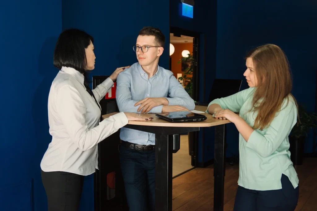 Deux femmes et un jeune homme qui discute autour d'une table