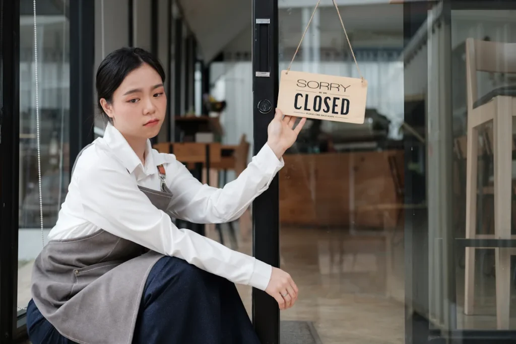 Une femme qui tient un panneau fermé devant une porte en verre