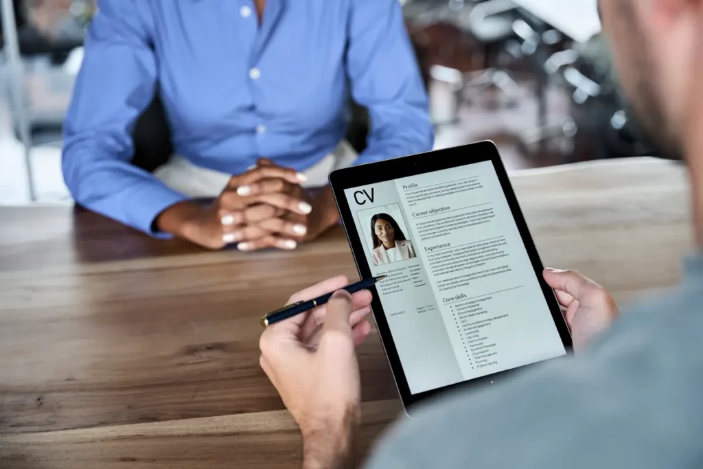 Une personne qui regarde un CV sur une tablette face à une personne