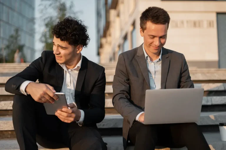 deux hommes qui prospectent en BtoB sur les réseaux avec un Smartphone et un ordinateur