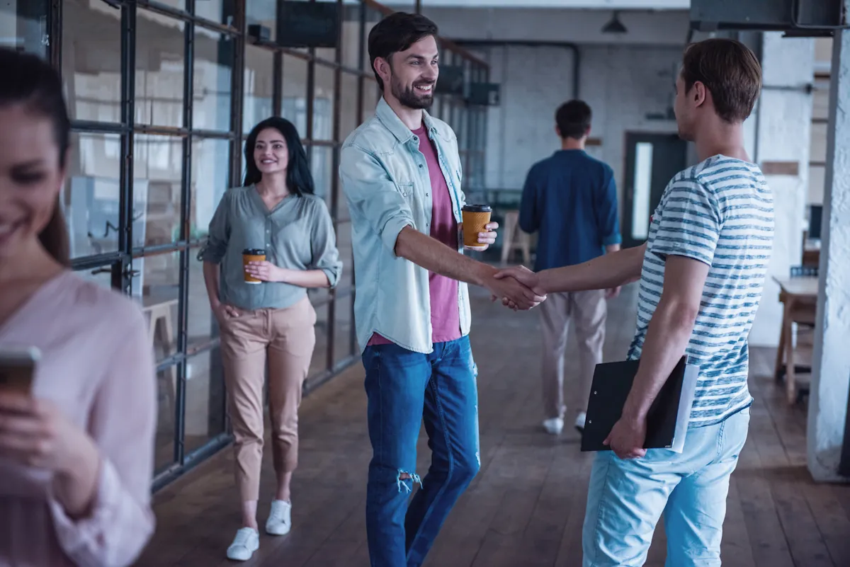 Un homme qui sert la main de son nouveau collègue pendant son processus d'onboarding