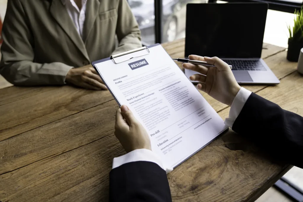 Une personne qui se présete en entretien devant une autre qui regarde un CV
